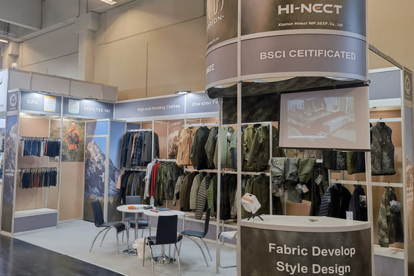 A clean, modern apparel factory floor with technicians working on seam-sealing machines, representing Hi-nect's manufacturing process.