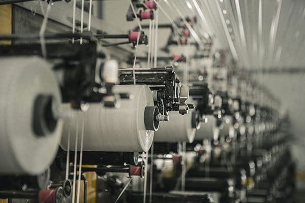 A massive industrial loom weaving technical fabric in a textile mill